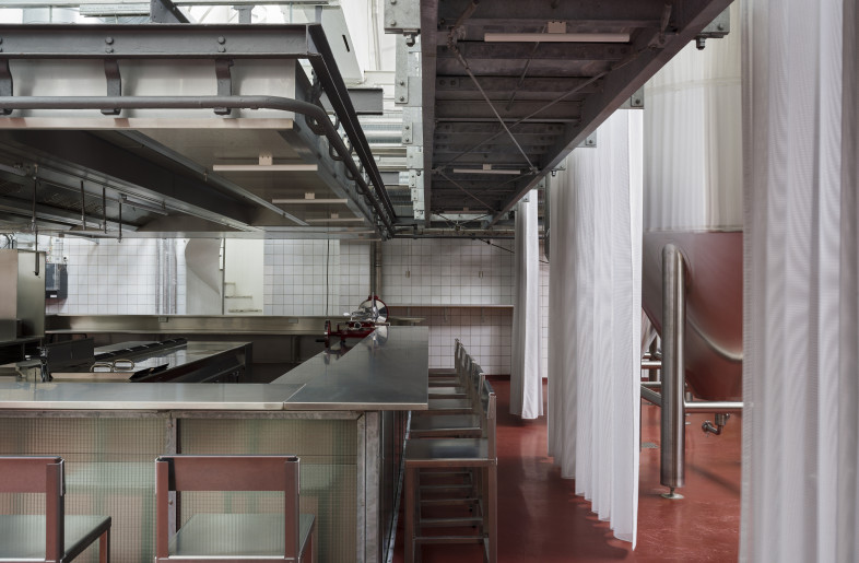 An open kitchen stands among the largest fermentation tanks. - Hampus Berndtson