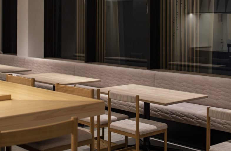 Custom chairs and the long bench seat are quilted with the same wing pattern as on the luminous walls to form a coherent interior space. - Keishiro Yamada