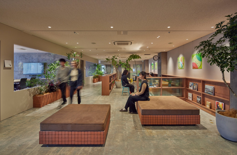 Reception. A place to greet visitors. To enrich the waiting time, we have installed books, large greenery with sunlight falling through the trees, and large comfortable benches. - FUMITO SUZUKI