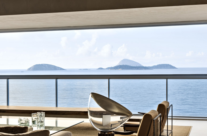Panoramic view of the sights of Rio de Janeiro and the sea at Ipanema beach from the living. Fusca sofa, designed by Arthur Casas for Micasa. Taccia table lamp, designed by Castiglione for Flos. Anette armchairs, designed by Jorge Zalszupin for ETEL Design. - Fran Parente