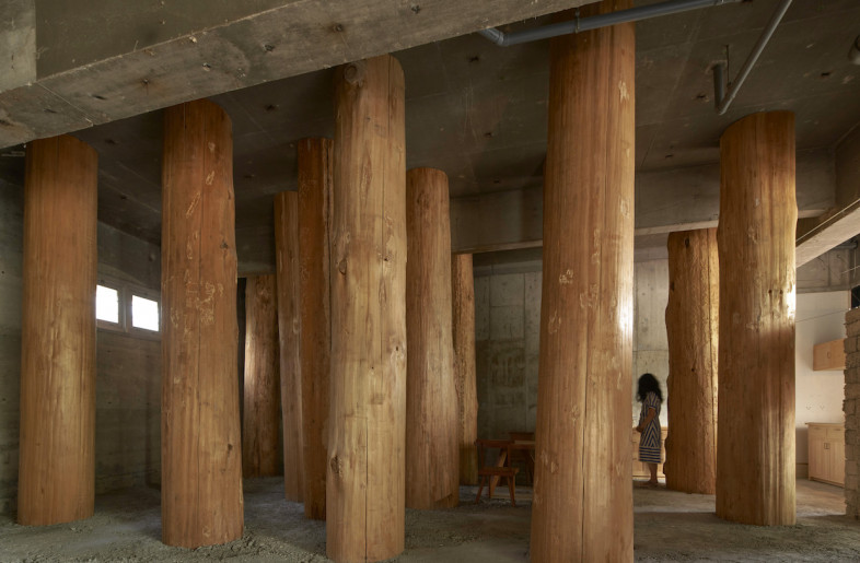 The space was stripped down to its concrete structure, and its concrete walls were left bare with the main design intervention incorporating large locally sourced tree trunks run vertically in an almost forest-like arrangement. - Edmund Sumner