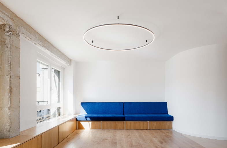 Blue elements accent the space such as the sofa, shelving unit and metal base of the countertop. - Aitor Estevez