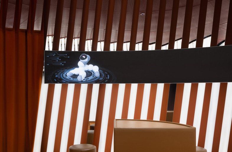 Key details include shard-like light fixtures that curve around the interior to the mandarin orange accent hue and reflective metal furniture finishes. - Wen Studio