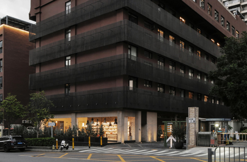 Renovated from an industrial building, the exterior of the hotel adopts a brick-red tone. Black aluminium grilles coil the building horizontally, enriching its visual appeal along with concealing outdoor machinery. - Xiaodong Xu