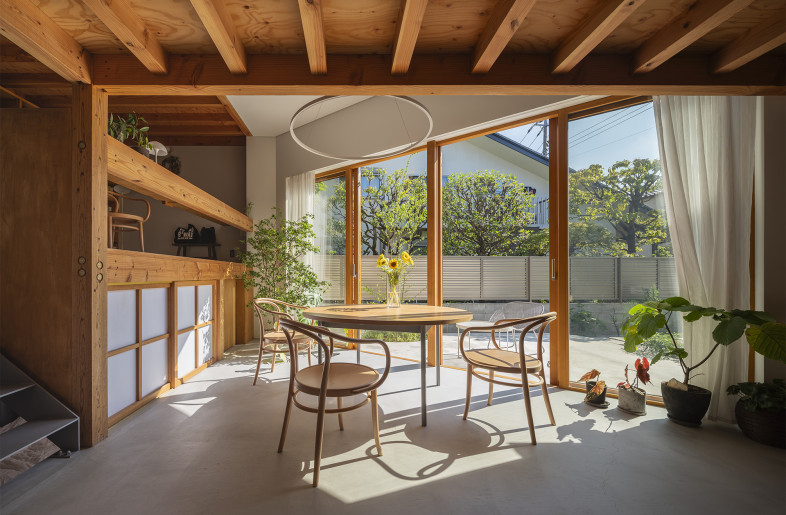 Open dining room (a component of 'Sankaku Common') designed with a large opening that connects seamlessly with the outside atmosphere and surroundings.This angled large opening provides views of the seasonally changing beautiful trees in the northwestern neighbor's garden while preventing inadvertent eye contact with them. - Shinkenchiku-Sha Co., Ltd.