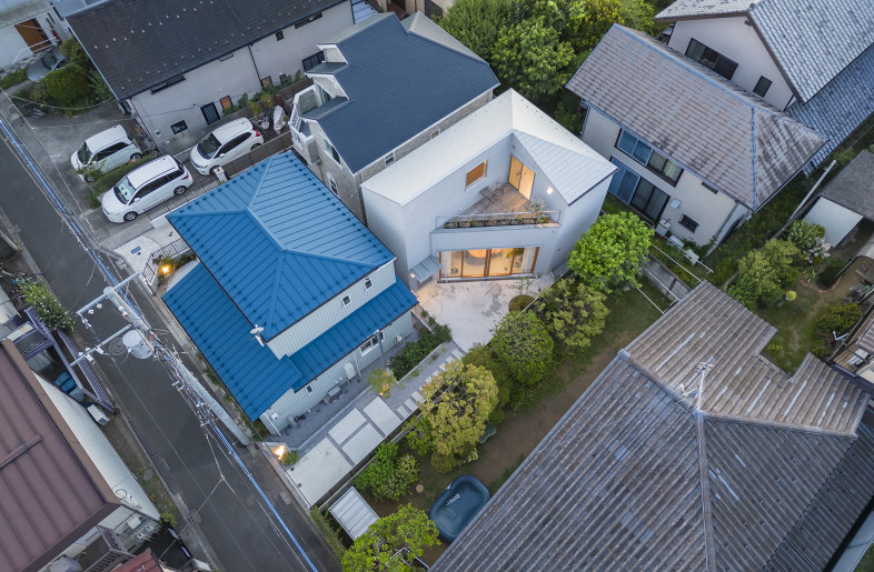 Overhead view from east.A unified landscape that integrates the open spaces, such as the gardens of both neighbors, the approach within the site, and 'Sankaku Common', has been created along the road. - Shinkenchiku-Sha Co., Ltd.
