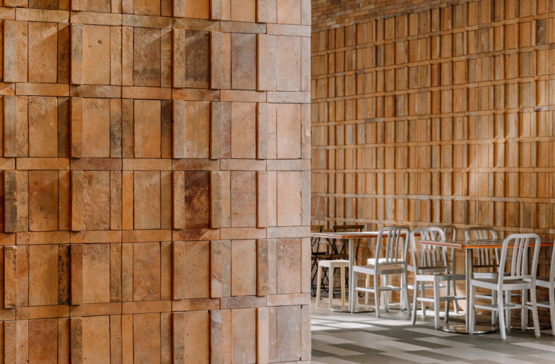 Tables and chairs are arranged around a central olive tree. - Wen Studio