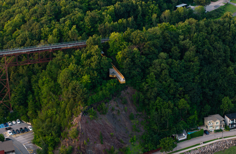 The highlight of the project is a striking pedestrian bridge, positioned perpendicular to the railway viaduct, extending over the archaeological remains, the cliffside, and above the St. Lawrence River— the very waterway that bore witness to the arrival of the first French explorers. This landmark structure offers a 360-degree perspective on history and landscape, framing breathtaking views of the river, horizon, and traces of the past. - Loïc Lefebvre