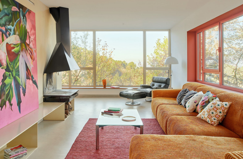 Around the corner, the living room features an inky metal open hearth atop a low built-in cupboard and colourful window frames. - José Hevia