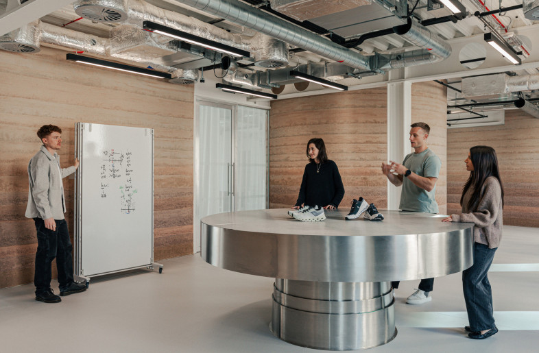 This collaboration area includes a table repurposed from On’s Regent Street store, set against handmade rammed earth walls crafted from naturally dyed southern English clay. - Chris Wharton