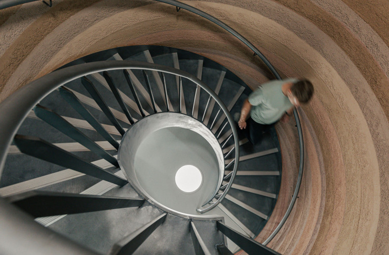 The striking staircase unites the two work levels, its sculptural, rammed earth finish evokes a cave-like feeling. As you ascend, the clay gradually lightens in colour.  A signature 'gem' moment for On. - Chris Wharton
