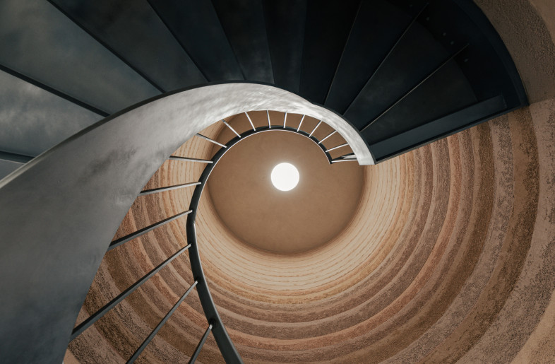 The striking staircase unites the two work levels, its sculptural, rammed earth finish evokes a cave-like feeling. As you ascend, the clay gradually lightens in colour.  A signature 'gem' moment for On. - Chris Wharton