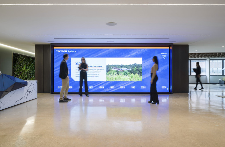 Visitors are greeted at a bold, faceted reception desk adjacent to a dramatic 160-square-foot LED display that showcases Textron Systems’ milestones, creating an immediate sense of innovation and technological legacy. - Evan Thomas/studiothomas