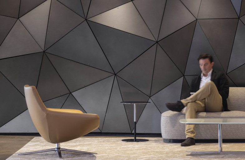 A sculptural feature wall of dark geometric panels that provides a striking backdrop to this intimate seating area. It also blends modern design with a sense of quiet sophistication. - Evan Thomas/studiothomas