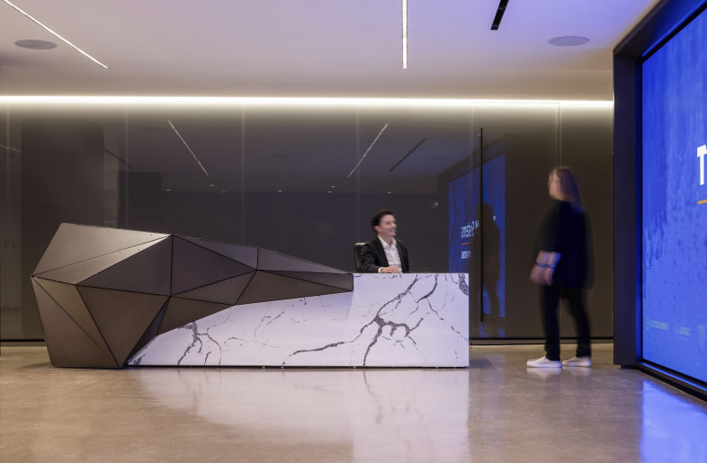 Set against a sleek backdrop, the angular reception desk with stone finish exudes modern sophistication and welcomes visitors into a space defined by innovation. - Evan Thomas/studiothomas
