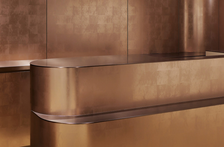 Reinforcing the striking impression of the space, the copper on the front gate is layered into the back wall and furniture. - SATOSHI SHIGETA