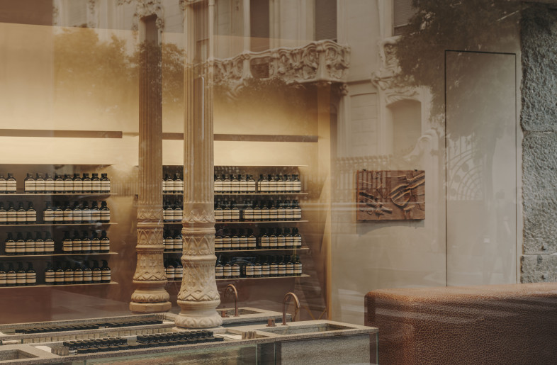 Interior of Aesop Las Salesas, showing the different furniture through the glass window with the Longoria Palace reflected. - Salva López