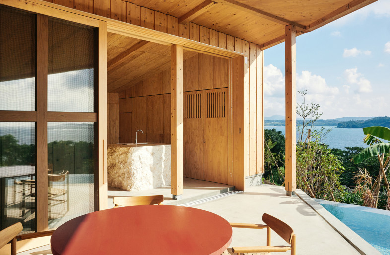 The semi-outdoor dining, centered around a vermilion table, is seamlessly connected to the kitchen and the pool. - Ju Yeon Lee