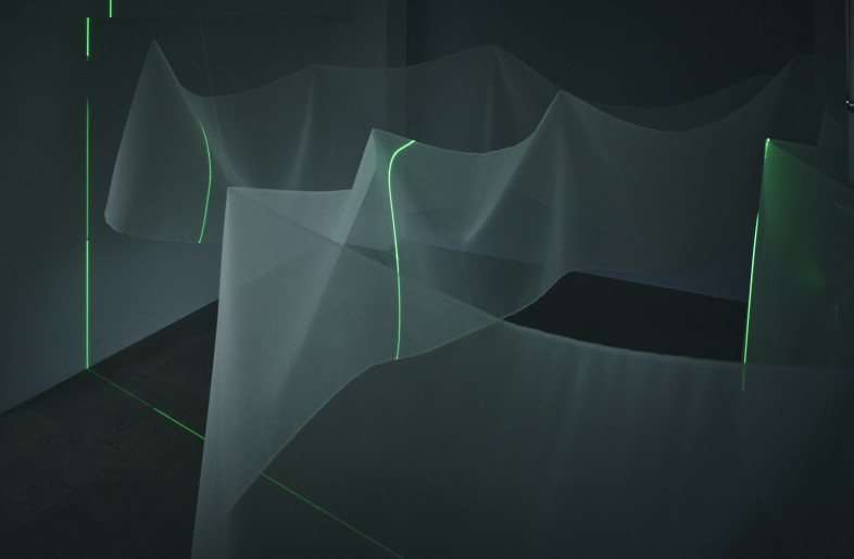 The green laser beam penetrates the textile and is also projected onto the entire space. Although the space is always the same, the light alone brings out a different expression of the space. - Masaki Ogawa