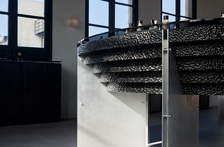 A sculptural perfume display at Elorea blends hand-chiseled blackened wood with CNC-milled aluminum, embodying a tactile tension between craft and precision. - Ye Rin Mok