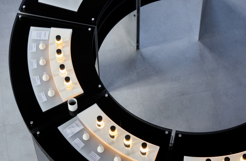 A closer overhead look at Elorea’s curved displays reveals a chromatic spectrum of scents and textures, arranged with ritualistic precision across illuminated plinths. - Ye Rin Mok