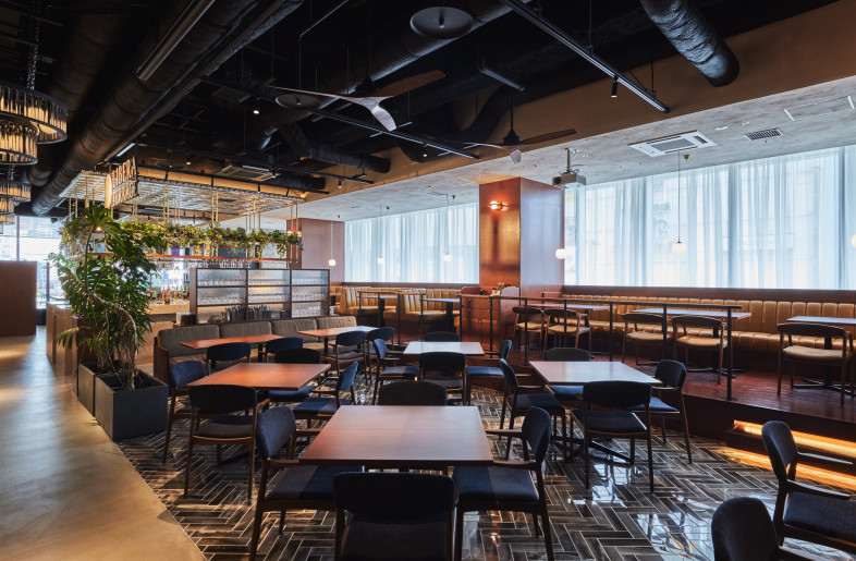 Restaurant Seating with Layered Perspectives. Tiered seating in the restaurant ensures an open sightline throughout the space, enhancing the dining experience and visual connectivity. - Photographer Shinsui Ohara
