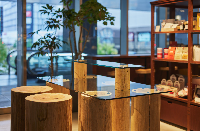 Food Retail Display with Natural Wood. Natural logs are ingeniously repurposed as display fixtures for the food retail section, adding a touch of natural warmth and authenticity. - Photographer Shinsui Ohara