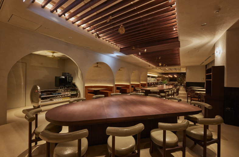 Adaptable Seating in the Casual Zone. A large, transformable table creates diverse and inviting spaces for various group sizes and interactions near the entrance. - Photographer Shinsui Ohara