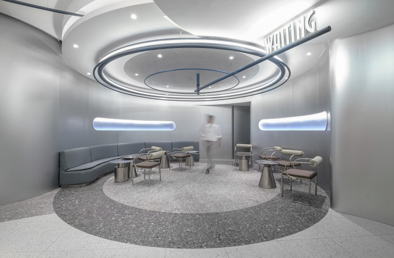 The waiting lounge, with its curved seating and subtle lighting, offers a relaxing space for patrons to prepare for their cinematic adventure. - Design Action