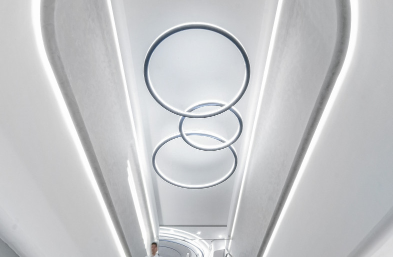 Taking the escalator down from the lobby, the soaring ceiling height and streamlined light trough design create a spaceship-like atmosphere, guiding audiences to another floor. - Design Action
