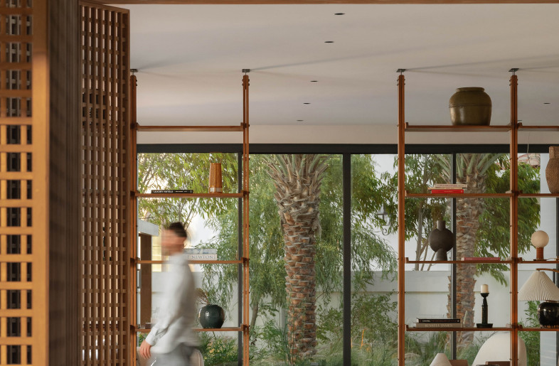 Bespoke shelving, lighting, coffee table, and seating—each element an invitation to linger and pause in the living room. Full-length windows create a seamless connection to the outdoors. - Natelee Cocks