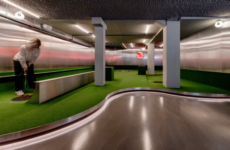 Islands of grass and aluminum under soft lighting give the mini-golf area a distinctive atmosphere. The large islands interact with the building’s structure and “float” above the concrete floor. - Ben Speck