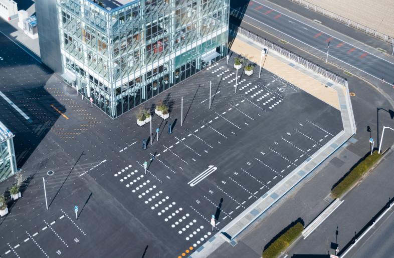 The surrounding roads and the site are continuous without boundaries, and graphics on the asphalt extend into the building. - Takumi Ota