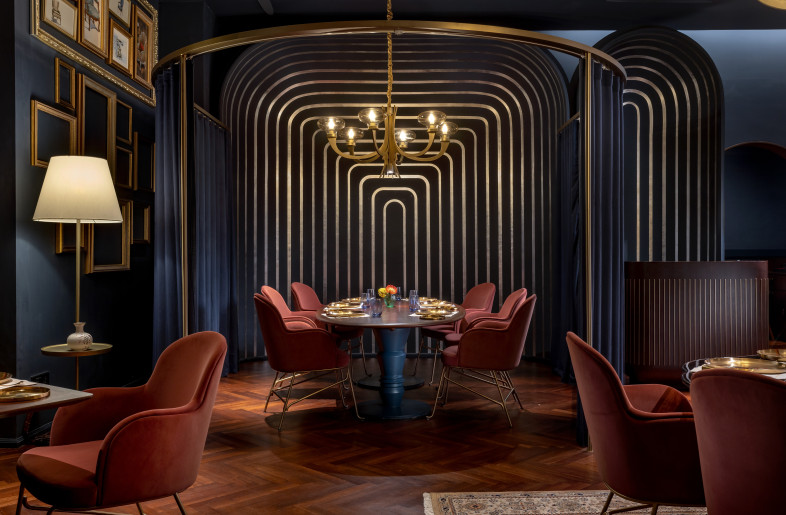 Custom-designed dining tables cast diffused reflections of the overhead lights, adding warmth and intrigue to the space. - Jeetin Sharma
