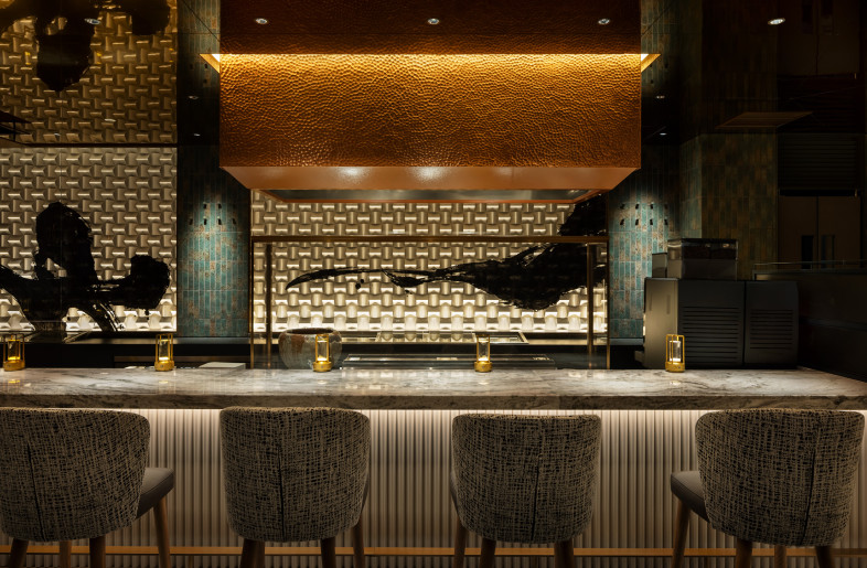 The space features a striking combination of calligraphy and a copper hood. The hood showcases tsuchime, a traditional Japanese hand-hammering metalwork technique, while the calligraphy is expressed through sandblasting on glass. - Nacasa & Partners
