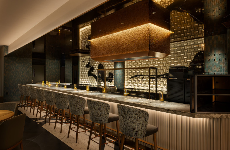 The space features a hood incorporating traditional Japanese craftsmanship and calligraphy as an art form. The striking, large-scale counter is made from Brown Fantasy, a type of granite sourced from Indonesia. By blending the spirit of Japanese aesthetics with foreign materials, the design creates a unique oriental atmosphere. - Nacasa & Partners