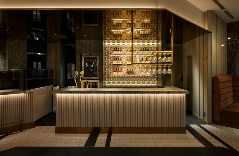 A drink counter is positioned in spatial continuity with the main counter, creating a sense of unity and rhythm throughout the space. - Nacasa & Partners