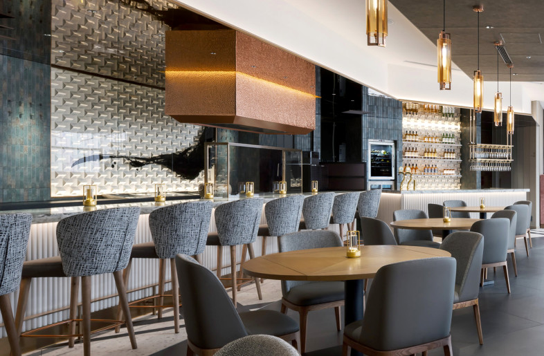 During the day, the space is filled with natural light, creating a bright and comfortable atmosphere. The theme colors—orange and patina green, derived from the aging of copper—stand out beautifully within the interior. - Nacasa & Partners