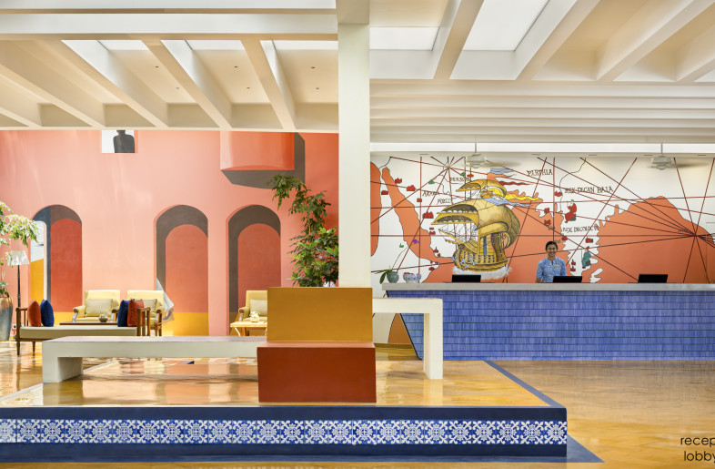 A view of the reception counter which mimics a docked ship. With its cast concrete counter top, and mural depicting the sea voyage of Vasco Da Gama, it welcomes guests into the resort & initiates them on a unique  journey. The otla in the centre is reimagined as part of the renovation with the use of blue micro-concrete and tile details as well as tunable skylights above. - Andre Fanthome (Studio Noughts and Crosses)