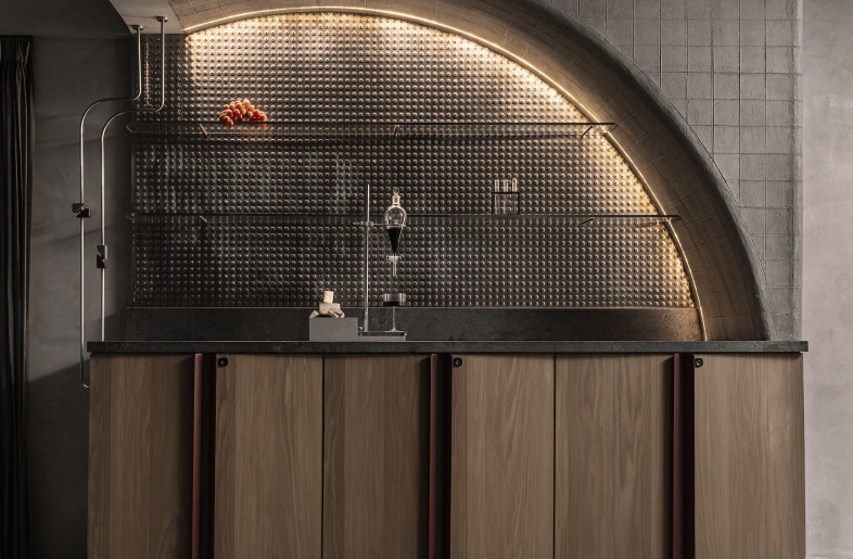 Custom oak veneer cabinetry with patinated brass pulls conceals integrated appliances. - Ishita Sitwala