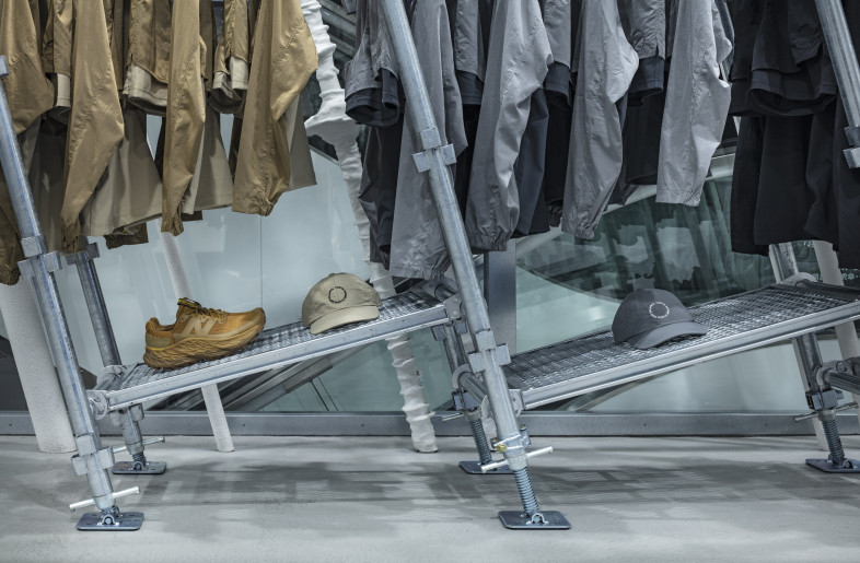 “Uni-ssentials by TDS" is an apparel collection that explores the essence of gender neutrality. Garments are displayed in various sizes, on tilted fixtures that follow the diverse hem lengths—visually embodying the concept. - Kenta Hasegawa