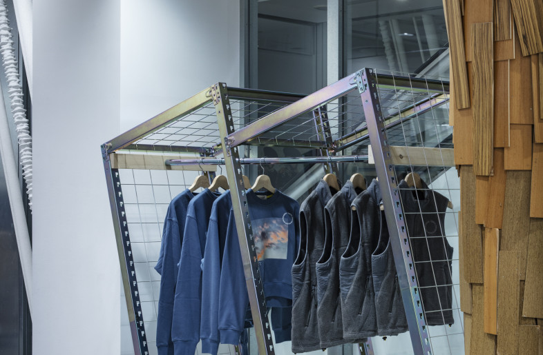For FW24, the repurposed steel racks were updated with a rainbow interference finish through chromate treatment, inspired by the blurred photo prints featured in the collection. A non-toxic trivalent chromium was chosen to achieve both aesthetics and sustainability, aligning with global environmental standards. Additionally, a matching shoe rack was created using scraps from the garment rack posts. - Kenta Hasegawa