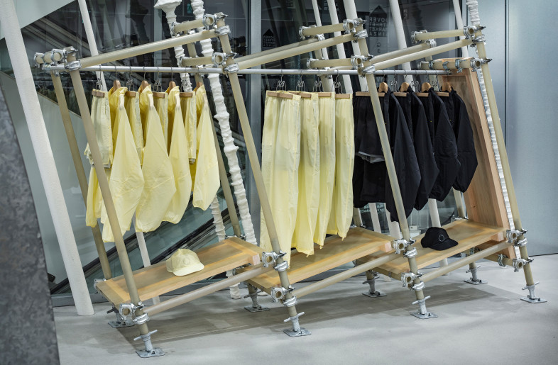 In SS25, handcrafted translucent FRP were used, allowing the wooden rafters under the shelf boards and the threaded post of the jack base to show through, creating visual harmony with the sheer apparel. - Kenta Hasegawa