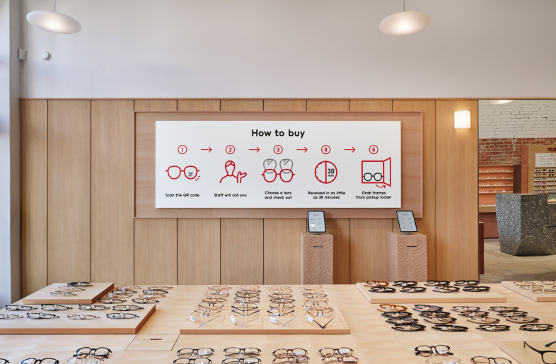 A ‘How to Buy’ panel, presented like an art piece, hangs on the oak wall, with the Naguri-carved reception stand placed in front. - Daici Ano