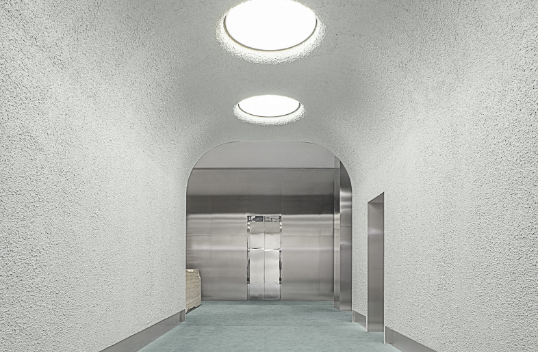 Gallery leading to the welcome desk. By analyzing the showroom through the lens of descent and ascent, a distinct chromatic journey emerges in the spatial design: from the sky-like hues at the entrance, transitioning into emerald green—symbolizing renewal—as one descends, to the mocha mousse tones reminiscent of the earth’s clay core. - Max Zambelli