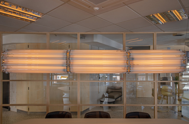 More than 100 fluorescent tubes were transformed into a horizontal suspended lamp in the meeting room. Lucas cleaned and reused the old tubes to create a simple and functional centrepiece, using only threaded rods, nuts, quick-connect clamps, and a central aluminium axis that also serves as a heat sink for the LEDs. - Asier Rua
