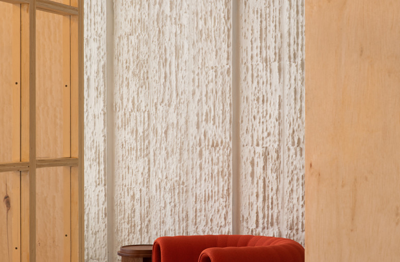 The ceiling tiles, typical of the 1970s, was a compact, non-recyclable fibre covered with a thin layer of plaster. All the 60 x 60 cm tiles were salvaged, cut into two equal halves, and then each half was split into two again using a device designed on-site, resulting in one straight side of 60 cm and another irregular side, leaving a depth of about 10 cm.  These new tiles were assembled into modules of 40 x 240 cm, with a plaster skin applied using compressed air to create an irregular texture on the wall. - Asier Rua