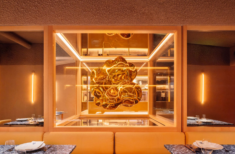 Below the ground floor and entrance, a golden “popcorn” sculpture floats like a caramelized cloud—both playful and precious. Framed by glass and warm timber, it anchors the lower-level dining space as a glowing centerpiece between art and atmosphere. - Francisco Nogueira