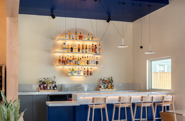 A recycled glass bartop and painted perforated metal bar shelving add visual interest. - Leonid Furmansky