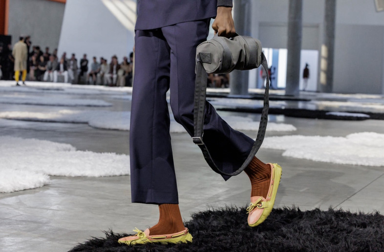 Concrete walls and floors were exposed, and the orange-painted metal enforcement grid gleamed in the sunlight. - Courtesy of Prada